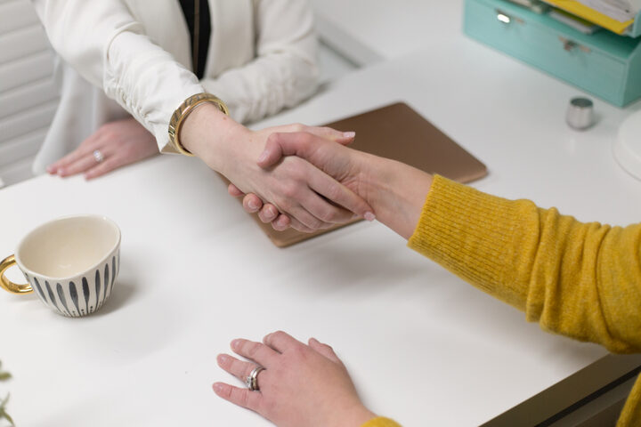 An adviser and a client shaking hands across a desk